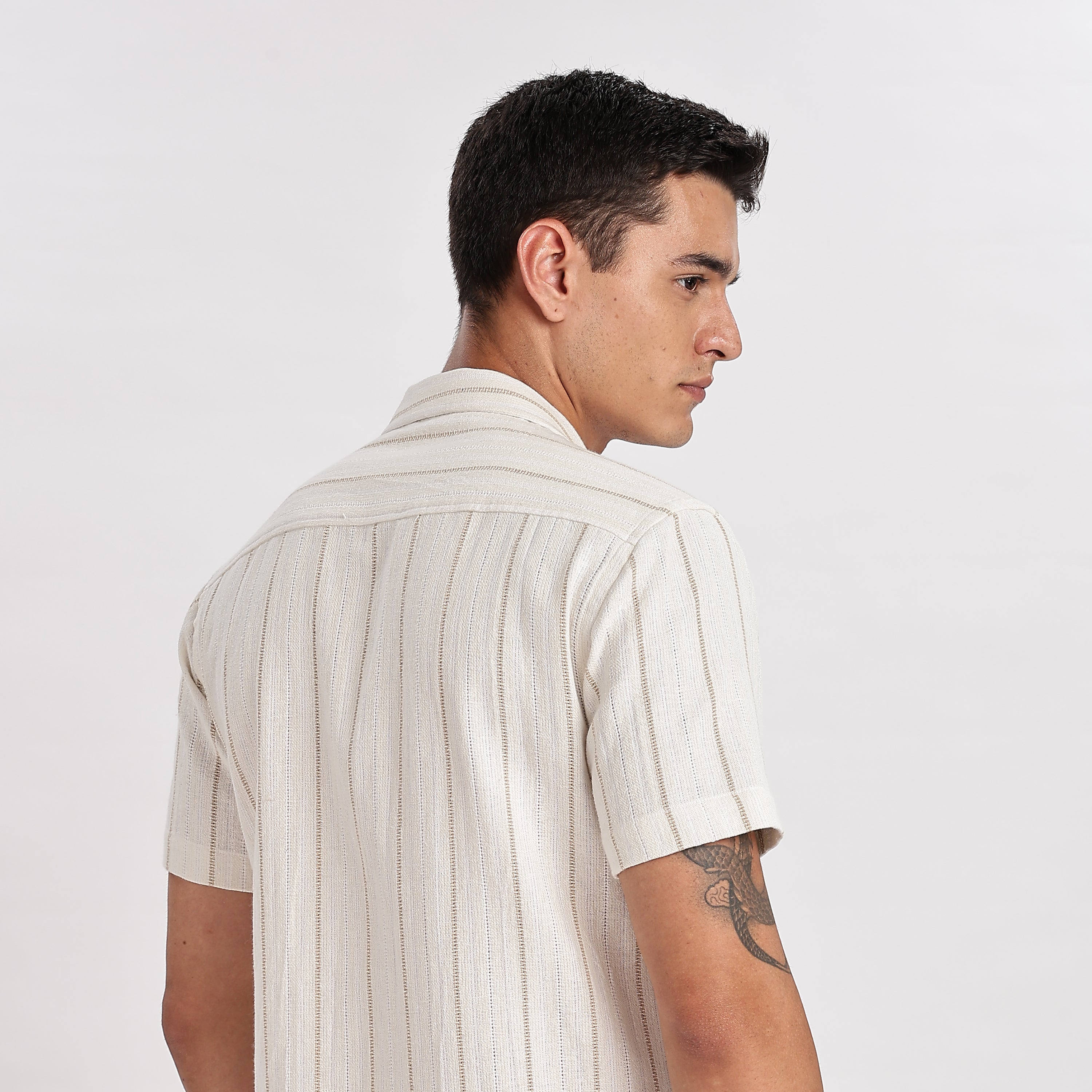 Man wearing a white striped shirt and beige pants on a white background