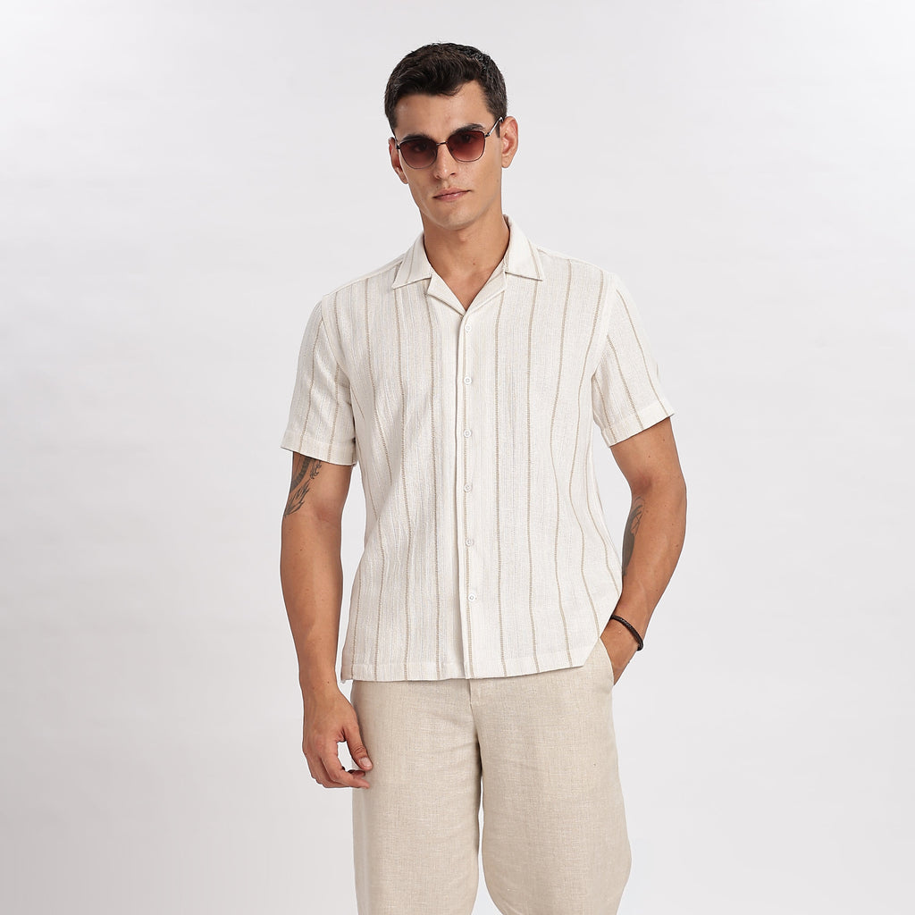 Man wearing a striped shirt, beige pants, and white sneakers on a white background