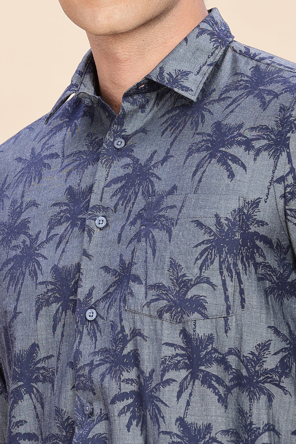 Close-up of a person wearing a blue shirt with palm tree pattern